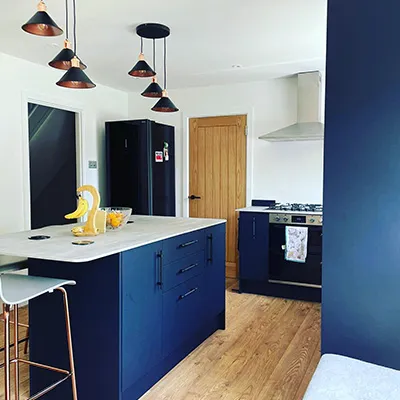 A kitchen with blue cabinets and white counter tops.